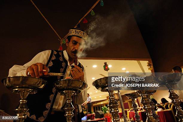Waiter wearing traditional Arab costume prepares on September 2, 2008 charcoal for waterpipes for customers who flood Beirut's cafes after the break...