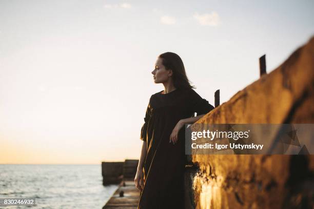 woman walking near the sea - schwarzes kleid stock-fotos und bilder