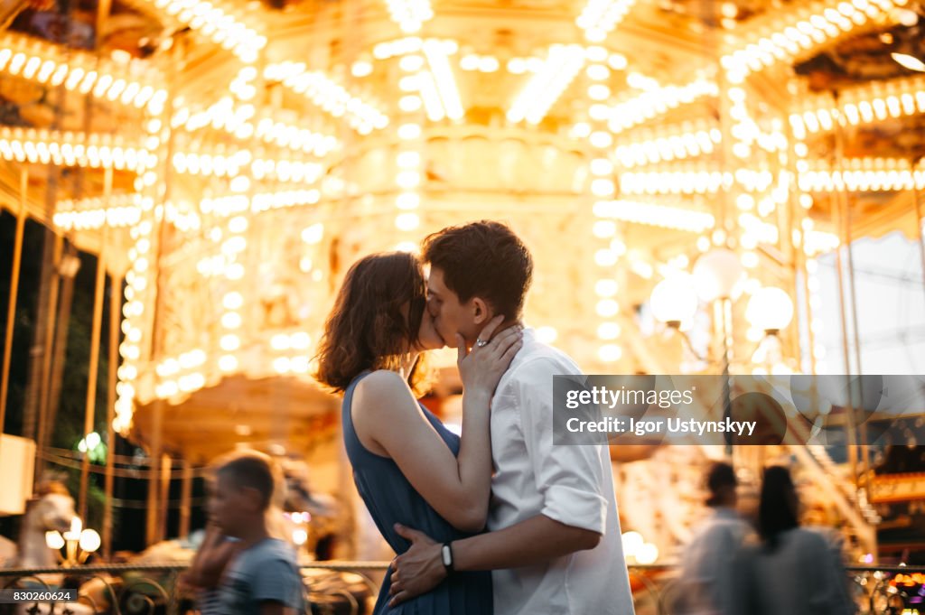 Couple kissing near the marry-go-round in the park