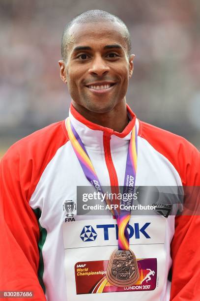 Bronze medallist Portugal's Nelson Evora poses on the podium during the victory ceremony for the men's triple jump athletics event at the 2017 IAAF...