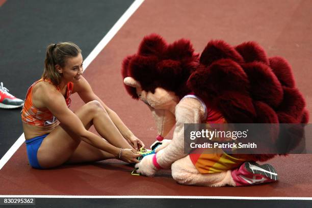 Hero the Hedgehog helps Nadine Visser of the Netherlands with her cleats after she competed in the Women's 100 metres hurdles semi finals during day...