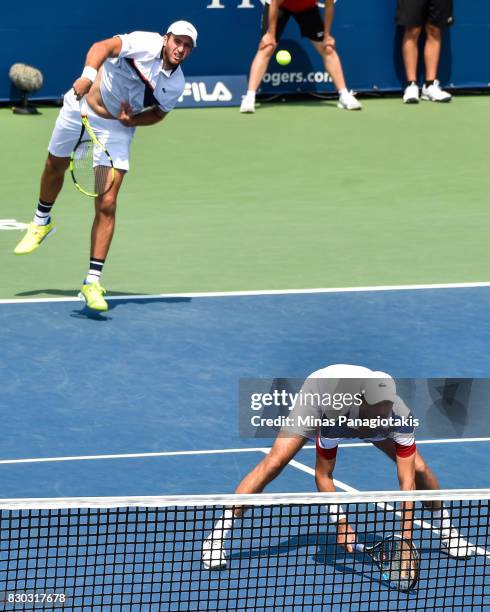 Fabrice Martin of France serves as teammate Edouard Roger-Vasselin ducks down in their doubles match against Raven Klaasen of Russia and Rajeev Ram...