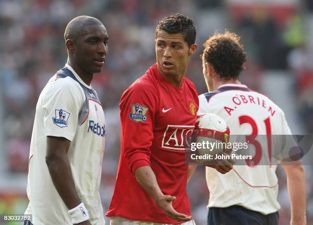 Jlloyd Samuel of Bolton Wanderers complains to Cristiano Ronaldo of Manchester United after Ronaldo won a penalty during the FA Premier League match...