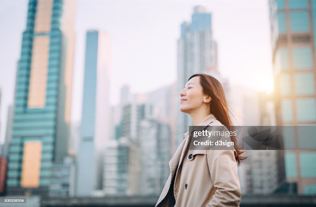 Beautiful woman taking a deep breath on city office roof terrace on a fresh morning