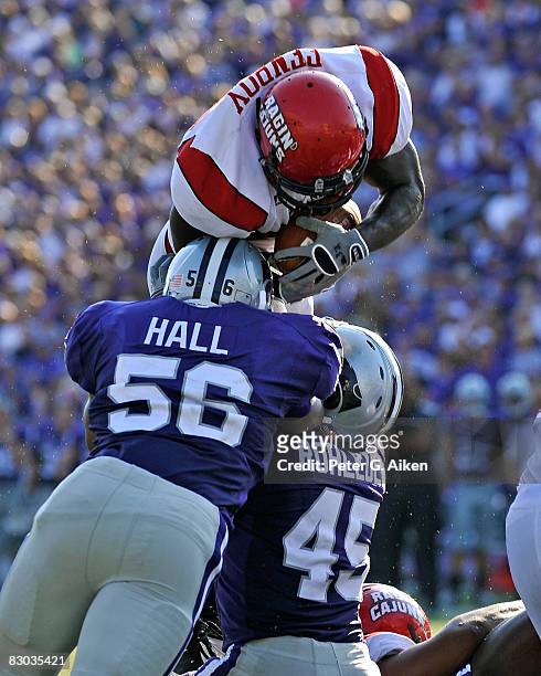Running back Tyrell Fenroy of the Louisiana-Lafayette Ragin' Cajuns tries to dive over the top of linebackers Olu Hall and Kevin Rohleder of the...