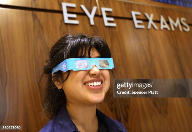 Warby Parker employee Karolyna Landin poses with a pair of solar eclipse glasses that the eyeglass store is giving out for free on August 11, 2017 in...