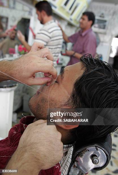 An Iraqi man has facial hair removed before having a hair cut and shave at the Najim barber shop in central Baghdad on September 28 2008, ready for...