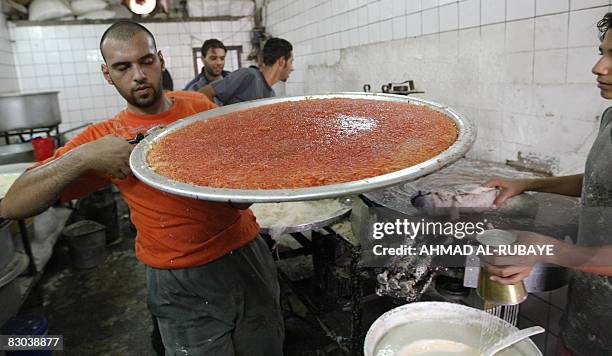 Bakery employee carries a tray of cooked "kunafa", a traditional Middle Eastern dessert, in Baghdad's Karrada district on September 1, 2008. Prime...