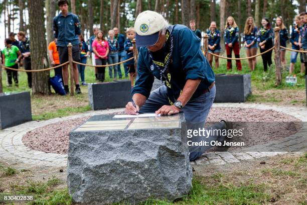 Swedish King Carl Gustav writes his name on a stone which is part of a sculpture to remember previous jamboree's during his visit to the scouts...