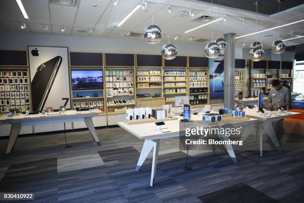 An employee uses a tablet as Apple Inc. And Samsung Electronics Co. Smartphones are displayed for sale at an AT&T Inc. Store in Newport Beach,...