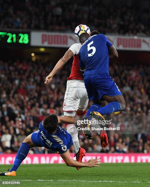 Olivier Giroud of Arsenal scores his team's fourth goal despite the attentions of Harry Maguire and Wes Morgan of Leicester City during the Premier...