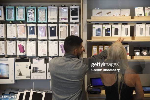 An employee assists a customer shop for Apple Inc. IPhone accessories at an AT&T Inc. Store in Newport Beach, California, U.S., on Thursday, Aug. 10,...