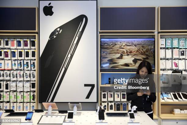 An employee uses an Apple inc. IPhone at an AT&T Inc. Store in Newport Beach, California, U.S., on Thursday, Aug. 10, 2017. AT&T Inc. Shares surged...
