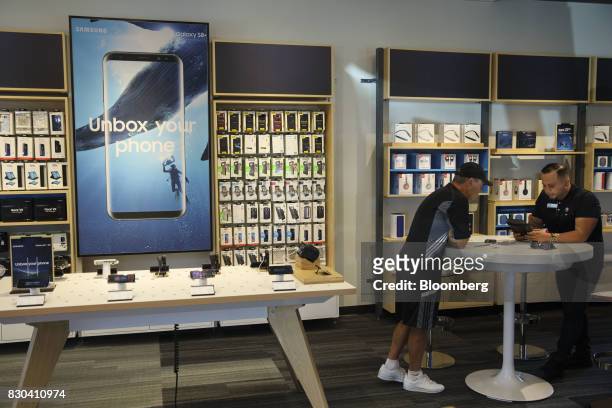 An employee assists a customer at an AT&T Inc. Store in Newport Beach, California, U.S., on Thursday, Aug. 10, 2017. AT&T Inc. Shares surged the most...
