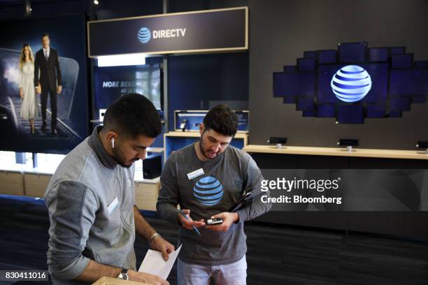 Employees speak at an AT&T Inc. Store in Newport Beach, California, U.S., on Thursday, Aug. 10, 2017. AT&T Inc. Shares surged the most in more than...