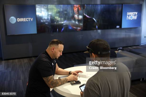 An employee uses a tablet computer to complete a purchase for a customer at an AT&T Inc. Store in Newport Beach, California, U.S., on Thursday, Aug....