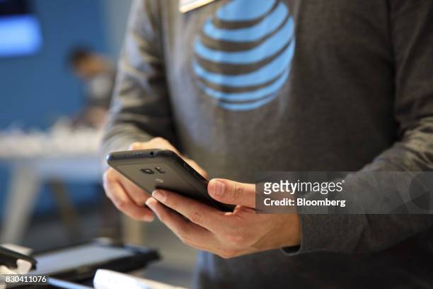 An employee assist a customer with a smartphone at an AT&T Inc. Store in Newport Beach, California, U.S., on Thursday, Aug. 10, 2017. AT&T Inc....