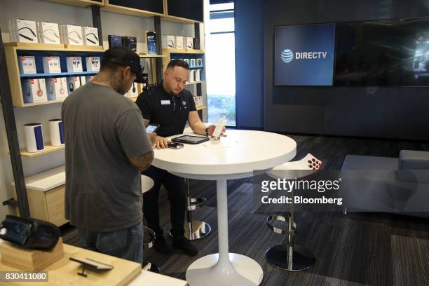 An employee uses a tablet computer to complete a purchase for a customer at an AT&T Inc. Store in Newport Beach, California, U.S., on Thursday, Aug....