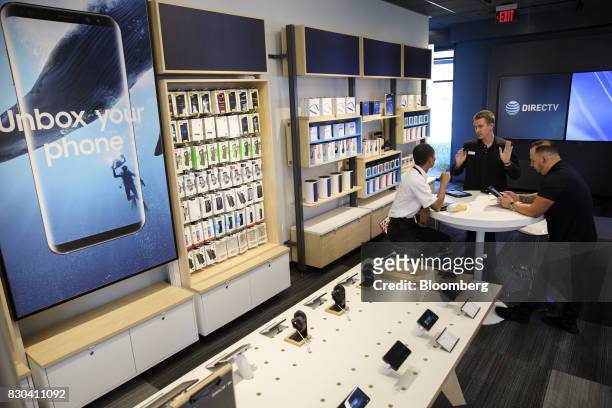Employees speak with a customer at an AT&T Inc. Store in Newport Beach, California, U.S., on Thursday, Aug. 10, 2017. AT&T Inc. Shares surged the...