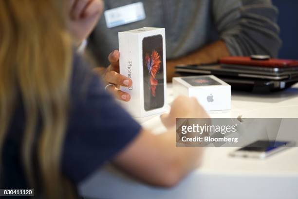 An employee assists a customer with an Apple Inc. IPhone at an AT&T Inc. Store in Newport Beach, California, U.S., on Thursday, Aug. 10, 2017. AT&T...