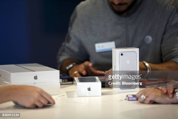An employee completes a purchase of Apple Inc. IPhones and iPads for a customer at an AT&T Inc. Store in Newport Beach, California, U.S., on...