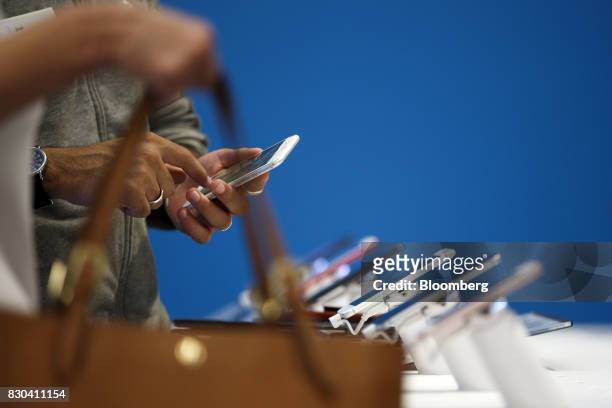 An employee assists a customer with an Apple Inc. IPhone at an AT&T Inc. Store in Newport Beach, California, U.S., on Thursday, Aug. 10, 2017. AT&T...