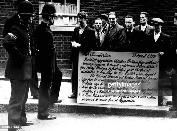 Group of men from the National Unemployed Workers Movement in Downing Street, London, with a 'protest postcard' listing various grievances and...