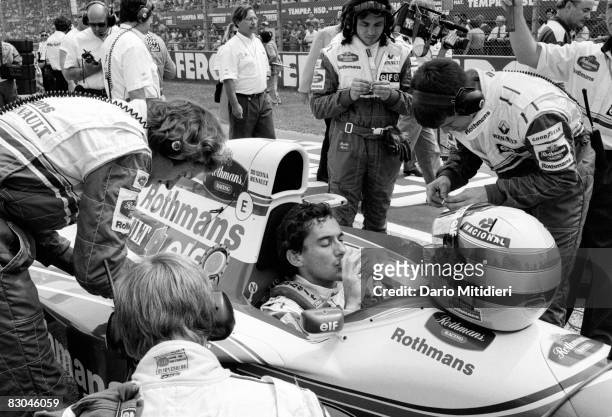Brazilian Formula 1 race car driver Ayrton Senna is surrounded by team mechanics as he drinks bottled water and waits on the starting line before the...