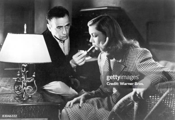 American actor Humphrey Bogart lights a cigarette for actress Lauren Bacall in a still from the film 'To Have and Have Not', directed by Howard...