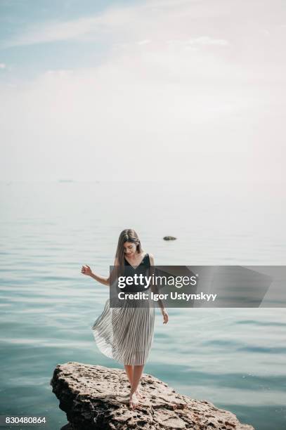 woman standing  on the rock near the sea - white style at quay stock pictures, royalty-free photos & images