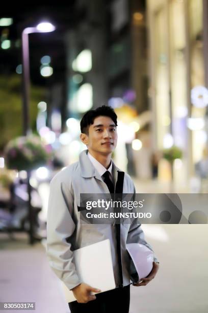 businessman holding hard-hat and file - a hard days night imagens e fotografias de stock