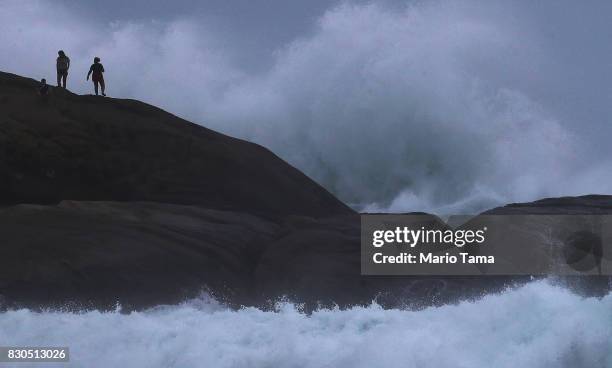 People stand on Arpoador rock during strong winter swells on the Atlantic Ocean on August 11, 2017 in Rio de Janeiro, Brazil. Waves were measured as...