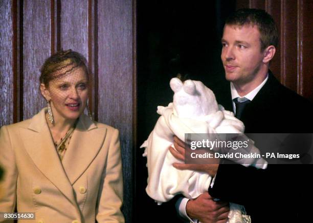 American singer Madonna and British film director Guy Ritchie with their four-month-old baby son Rocco, wrapped in a white christening gown, after...