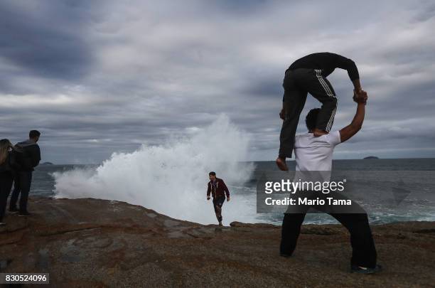 Circus performers practice a pose on Arpoador rock during strong winter swells on the Atlantic Ocean on August 11, 2017 in Rio de Janeiro, Brazil....