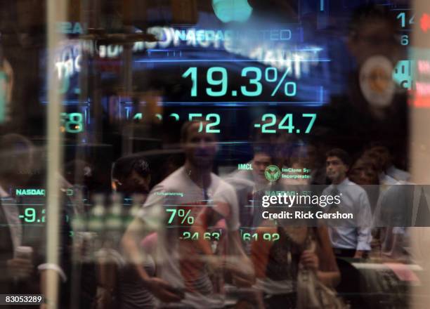 Passersby watch as the stock numbers are posted at the close of the market on the Nasdaq building in Times Square September 29, 2008 in New York...