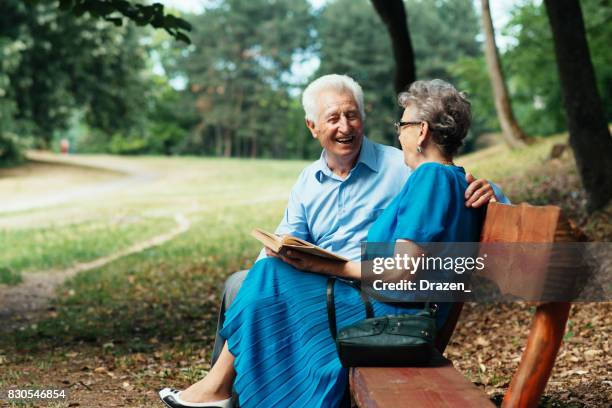 personas mayores leer libro en el parque - mujer leyendo libro en el parque fotografías e imágenes de stock