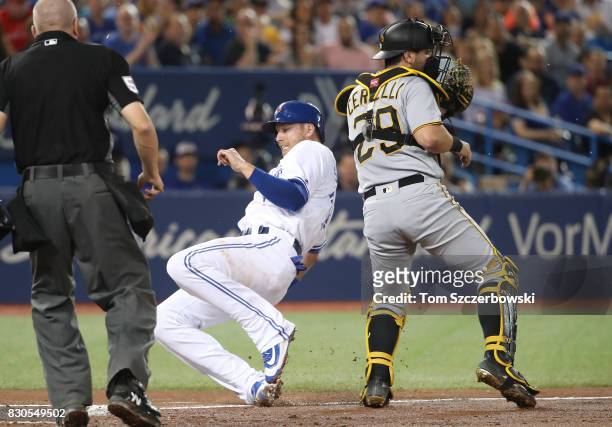 Justin Smoak of the Toronto Blue Jays slides across home plate to score a run on a sacrifice fly in the second inning during MLB game action as...