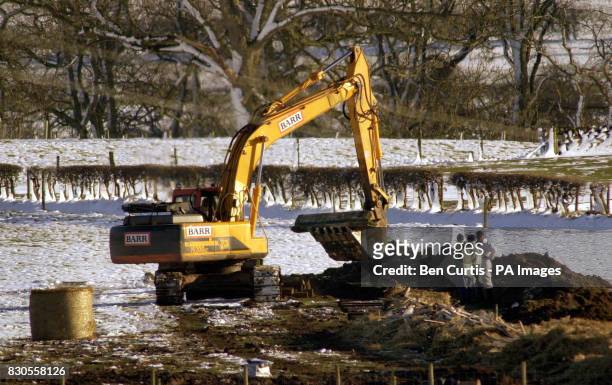 Mechanical diggers load railway sleepers into the trenches dug for the pyres at Parkhouse Farm in Canonbie, Dumfries and Galloway, ready for the...