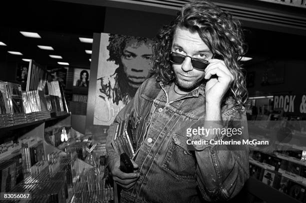 Australian singer songwriter Michael Hutchence of the rock band INXS, poses for a photo in front of a poster of Jimi Hendrix while shopping for CDs...