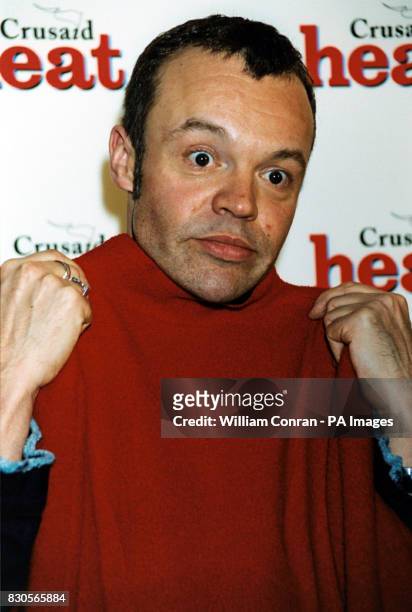 Comedian Graham Norton with a dress he bought which belonged to model Jerry Hall at the Heat Magazine & Crusaid celebrity auction at the Park Lane...