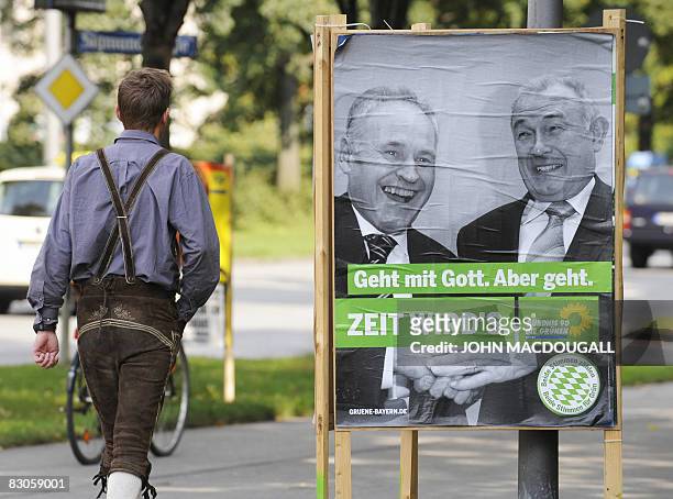 People walk past a Green Party campaign poster featuring Bavarian Premier and CSU main candidate Guenther Beckstein and CSU Chairman Erwin Huber in...