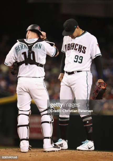 Starting pitcher Taijuan Walker of the Arizona Diamondbacks talks with catcher Chris Herrmann on the mound during the first inning of the MLB game...