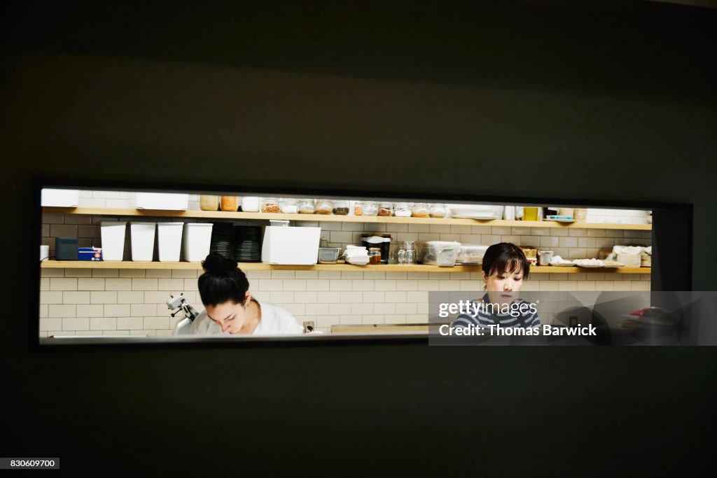 Two female chefs preparing for evening meal service in restaurant kitchen