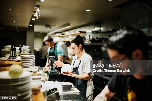 female chef working with block of parmesan cheese while preparing for dinner service in restaurant kitchen - catering occupation stock pictures, royalty-free photos & images