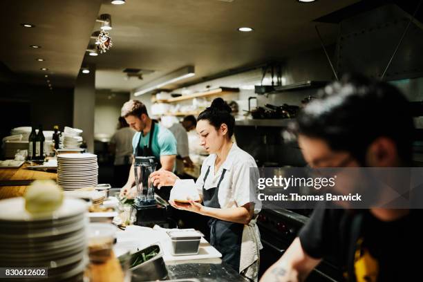 female chef working with block of parmesan cheese while preparing for dinner service in restaurant kitchen - profissão na indústria de alimentos - fotografias e filmes do acervo