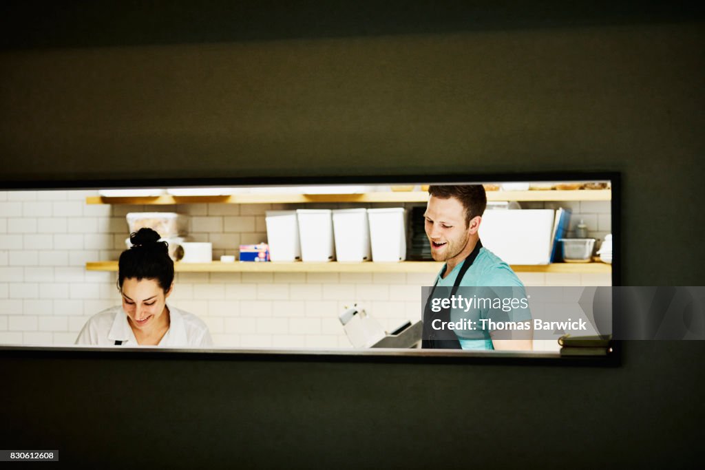 Smiling chefs in discussion in kitchen while preparing for dinner service