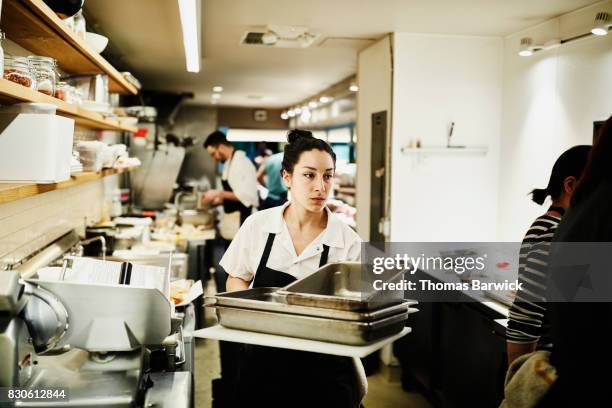 female chef carrying stack of dirty pans though kitchen to be cleaned - dirty pan stock pictures, royalty-free photos & images