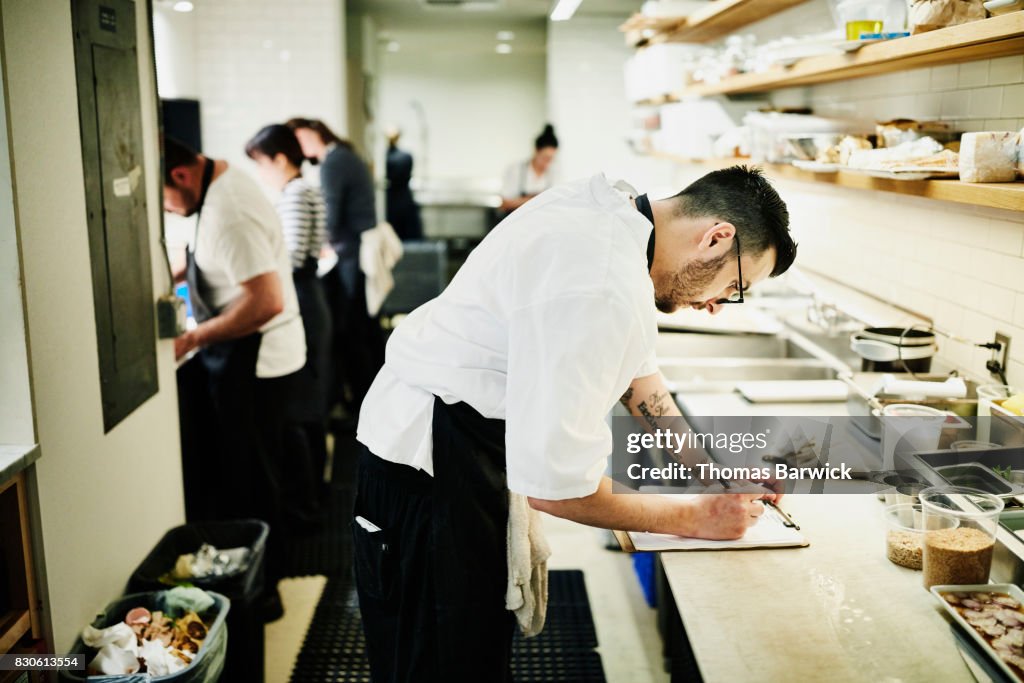 Chef checking list in restaurant kitchen while preparing for dinner service