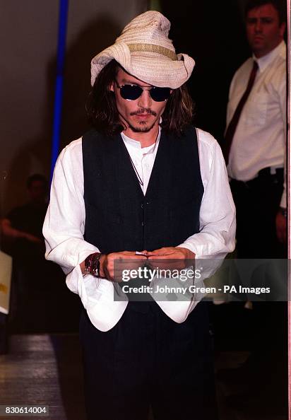 Actor Johnny Depp rolls a cigarette as he arrives for the premiere