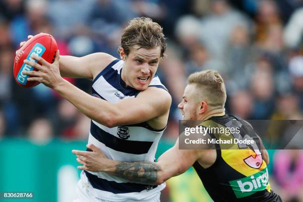 Jake Kolodjashnij of the Cats withstands a tackle from Brandon Ellis of the Tigers during the round 21 AFL match between the Geelong Cats and the...